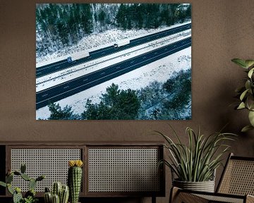 Snelweg door een besneeuwd boslandschap van bovenaf gezien