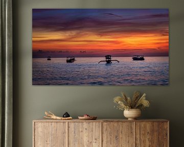 Boats bobbing in the ocean with a fiery sky as background