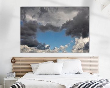 Wolken in alle kleuren: zwart, grijs, wit. Blauwe lucht op de achtergrond. van Robert Coolen