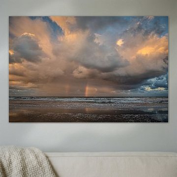 Herannahende Wolken über dem Meer mit Regenbogen von der aufgehenden Sonne.