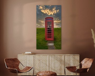 Cabine téléphonique rouge au coucher du soleil sur une prairie