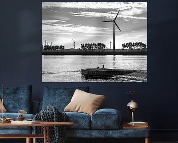 Silhouettes of a lone fisherman and wind turbines in backlight. (landscape shot) by John Duurkoop