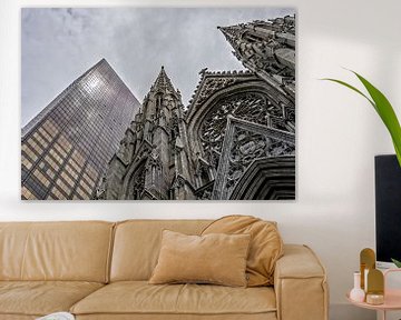 Looking up at St Patrick's cathedral in New York next to skyscraper. by John Duurkoop