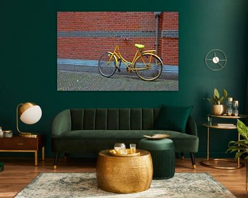Gele fiets tegen een rode muur