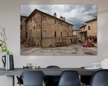 Red (Fiat 500) car in square in Bevagne, Italy by Joost Adriaanse