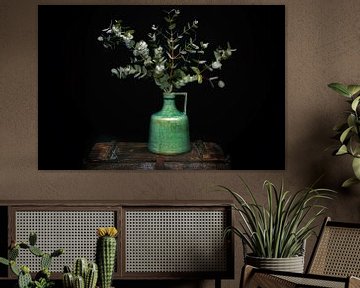 Groene kan met eucalyptus op een oude kist van marlika art