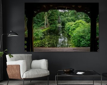 vue à travers une pergola en bois sur un étang bordé d'arbres au feuillage rouge et vert