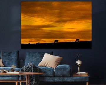 Zonsondergang boven  grazende koeien van John Kreukniet