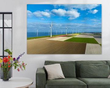 Windturbines op een dijk en voor de kust in de lente van bovenaf gezien