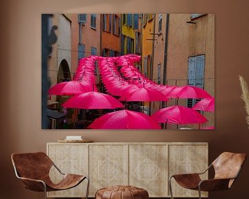 Felgekleurde, vrolijke roze paraplu's op een rij in het centrum van Grasse, in de regen van Studio LE-gals