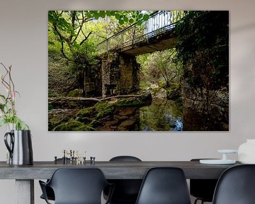 Oude brug over een snelstromend beekje in de bossen in Noord Spanje van Rick Van der Poorten