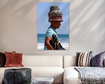 Beach vendor with pile of hats by Anne Ponsen