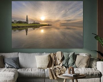 Zonsondergang boven het IJsselmeer en de toren van Hindeloopen gespiegeld in het stilstaande water.