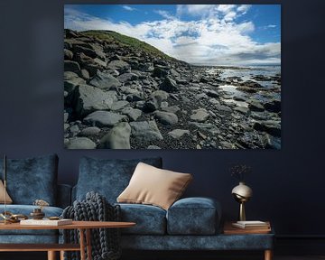IJsland - Groene heuvel achter stenige kust en weerspiegelend water van adventure-photos