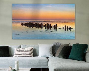 Wooden posts (breakwaters) in the Wadden Sea on Wieringen during sunset by Bram Lubbers