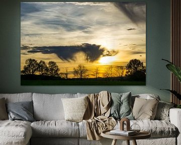 Oranje lucht met dramatische wolken als zonsondergang op landschap met brede weide van adventure-photos