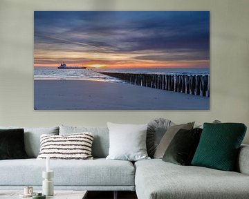 Vrachtschip vaart voorbij aan de kust van Zeeland tijdens zonsondergang. van Menno Schaefer