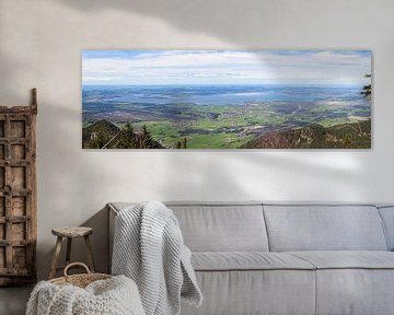 Panoramablick über eine grüne Landschaft mit Bergen im Vordergrund und dem großen Chiemsee in der Ferne von Thomas Heitz