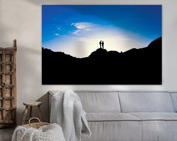 Silhouetten von zwei Personen, die bei Sonnenuntergang auf einem Berg stehen. Wout Kok One2expose von Wout Kok