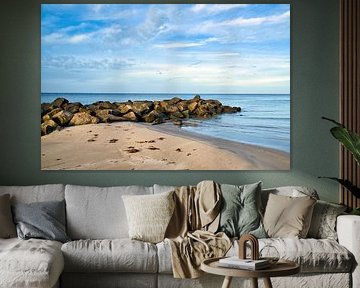 Stenen rotsblok steekt in zee op een zandstrand in Denemarken