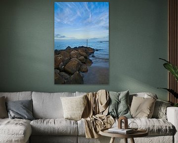 Stenen rotsblok steekt in zee op een zandstrand in Denemarken