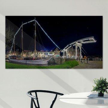 Panorama foto van een verlichte zeilboot en een ophaalbrug nabij de Drommedaris