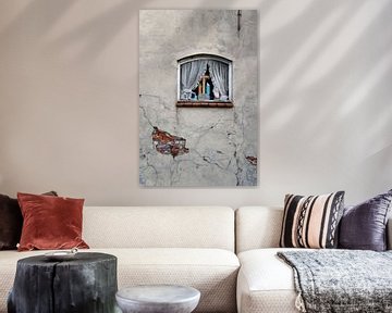 Verweerde muur met een raam met gordijnen en kruis met een Mariabeeld van Regina Elise