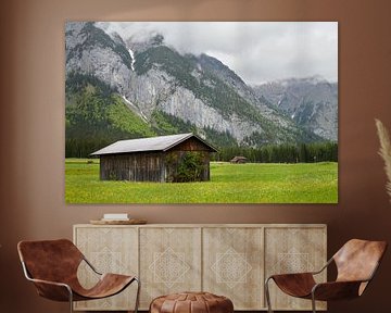 Austrian mountain landscape with wooden barn in meadow with yellow flowers.