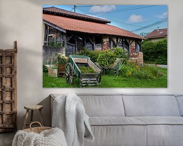 Surrounded by flowers half-decayed French barn, with old handcart.
