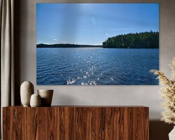 Lake in Sweden with white clouds, blue water and trees on the shore by Martin Köbsch