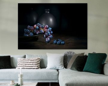 Purple blue grapes in a bowl on a rustic wooden table with vases