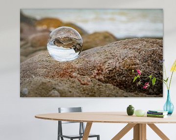 glazen bol met weerspiegeling van rotsen op het strand