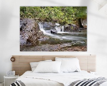 Kleine waterval in het bos met mos op stenen