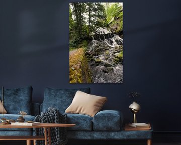 Kleine waterval in het bos met mos op stenen