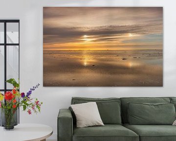 Das Wattenmeer mit einer seitlichen Sonne bei Sonnenuntergang mit Ameland am Horizont von Harrie Muis