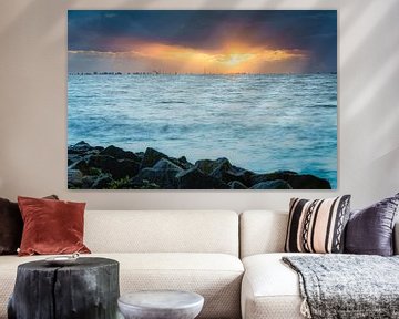 Skyline van Amsterdam met bewolkte zonsondergang met zonnestralen boven het wateroppervlak van de IJsselmeer van Fotografiecor .nl