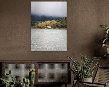 Een huis aan een meer met herfstkleuren in de bomen