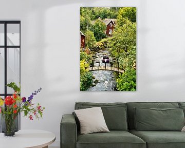 Fruitbomen bij een beekje met een bruggetje voor een rood houten huis in Zweden. van Martin Köbsch