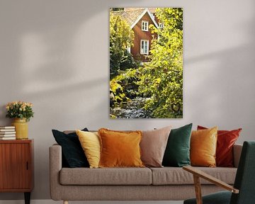 Fruitbomen bij een beekje met een bruggetje voor een rood houten huis in Zweden. van Martin Köbsch
