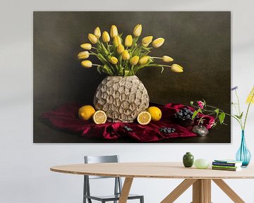 Stilleven met gele tulpen, citroenen en blauwe bessen op een rood tafelkleed