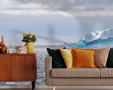 Adeliepinguine auf einer Eisscholle im Ozean mit weiteren Eisbergen im Hintergrund.