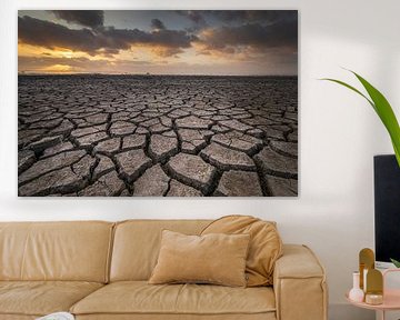 Droogte aan het wad onder een dreigende lucht tijdens zonsondergang