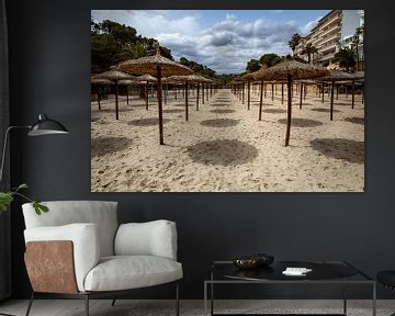 Reihen von Sonnenschirmen an einem leeren Strand auf Mallorca von Wim Brauns