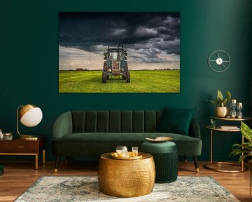 Tractor in the Frisian countryside with a heavy cloudy sky above. by Harrie Muis