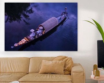 Lighting candles in baskets on the river by Anges van der Logt