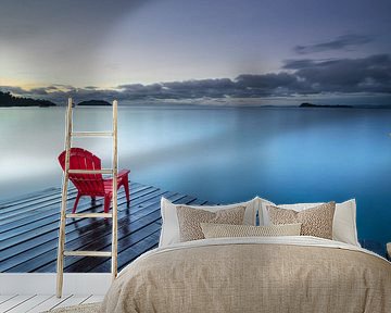 Rode plastic stoel op de pier bij het Sentani meer