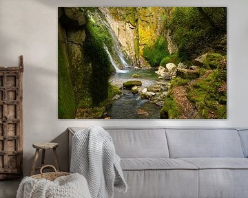 A majestic waterfall cascading down between overgrown rocks. by Wolbert Erich