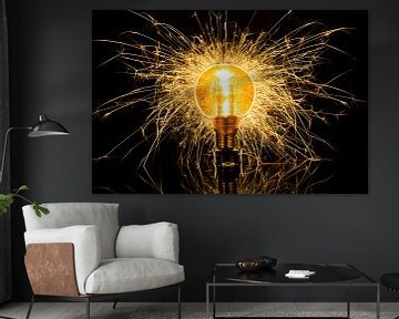Een gloeilamp die explodeert in een zee van gouden vonken, symbool voor inspiratie, creativiteit en energie. van Peter van Dam