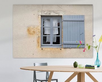 Blauw kozijn en luik in oude Franse gevel met was die hangt te drogen