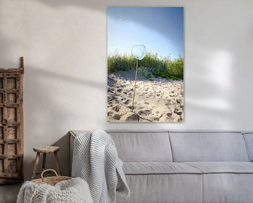 Blauw schepnet met houten paal op een zandstrand met blauwe lucht.